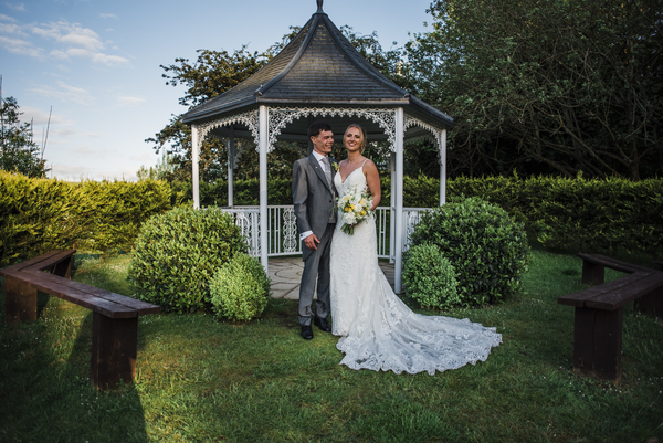 Bride and groom standing at gazebo 